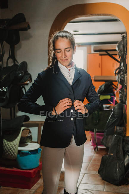 Woman in closet with staff getting dressed for horse riding — Stock Photo