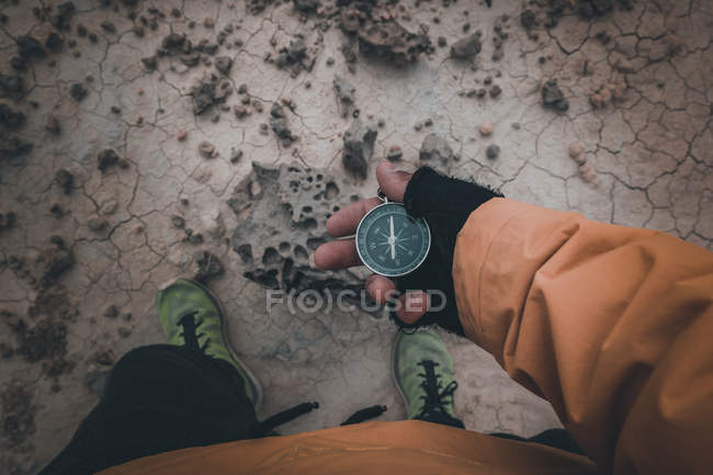 Closeup of hand in black fingerless glove holding compass on desert place — Stock Photo
