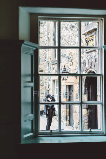 Vista a través de un viejo marco de ventana con un edificio de piedra envejecido detrás en luz natural suave, Escocia - foto de stock
