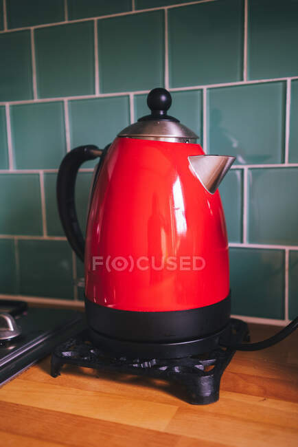Старомодний електричний чайник, червоний колір на дерев'яному приладі на кухні, Шотландія. — стокове фото