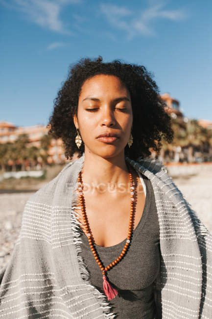 Афроамериканець молода жінка розмірковуючи в поставі Lotus йоги на піщаному пляжі в світлий день — стокове фото