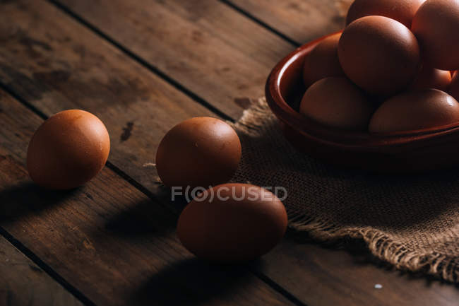 Ovos de galinha com tigela e saco em mesa de madeira — Fotografia de Stock