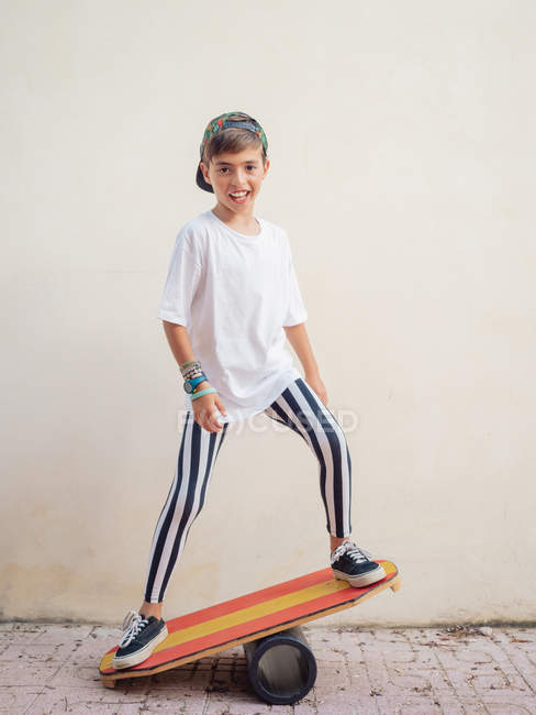 Stilvolle niedliche Junge in trendigen Klamotten Durchführung Trick auf hellem Brett und Blick auf die Kamera auf weißem Hintergrund — Stockfoto