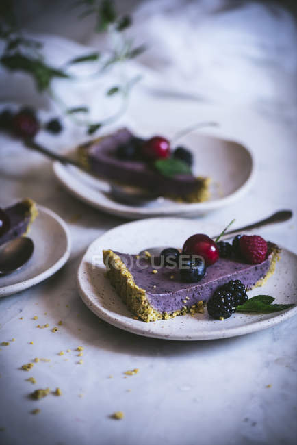 Pedaço de bolo saboroso com bagas de verão na placa na mesa branca — Fotografia de Stock