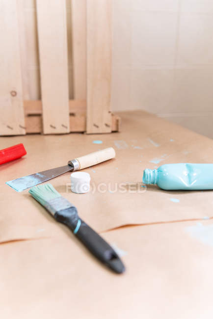 Wooden box with paint bottle and tools on table — Stock Photo