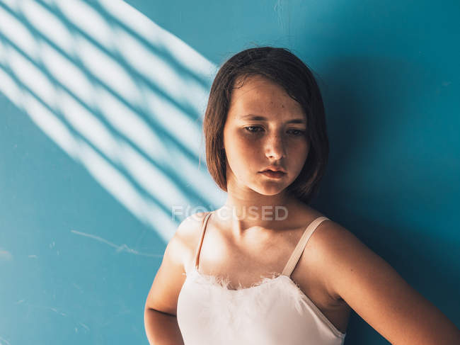 Балерина стоит с грустным лицом у голубой стены — стоковое фото