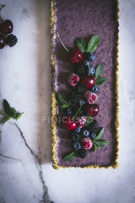 Вкусный прямоугольный торт украшенный летними ягодами на белом столе — стоковое фото