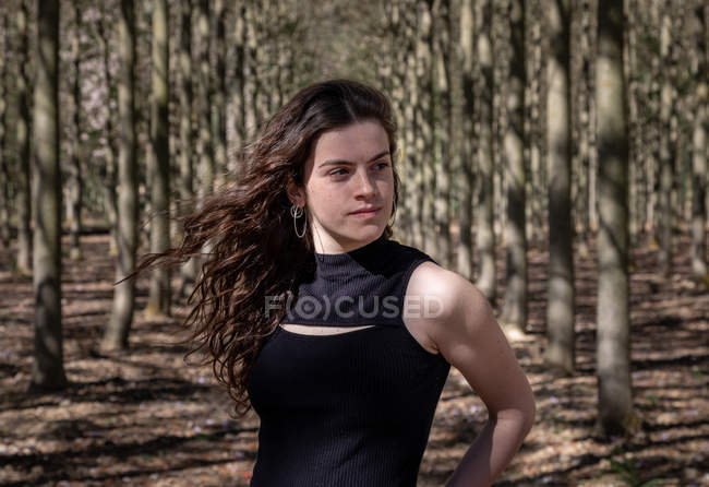 Giovane femmina in piedi nella foresta piena guardando lontano — Foto stock