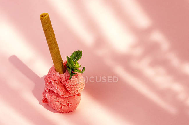 Strawberry ice cream scoops with waffle stick and mint leaves on pink background — Fotografia de Stock