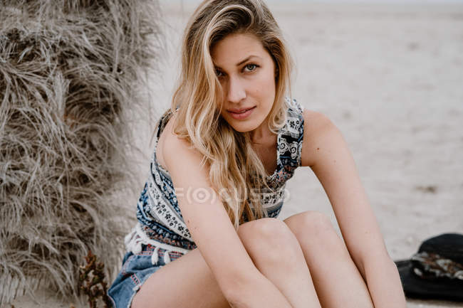 Ritratto di giovane bella donna bionda seducente seduta sulla spiaggia e che guarda la macchina fotografica — Foto stock