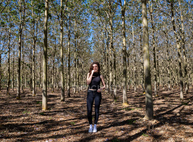 Молодая женщина стоит в лесу и улыбается — стоковое фото