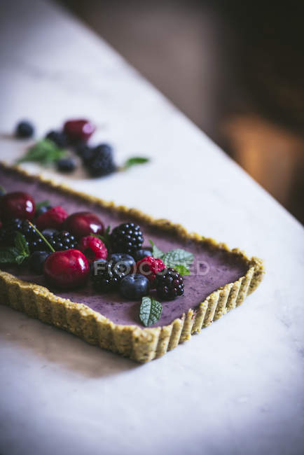 Tasty rectangular cake decorated with summer berries on white table — Stock Photo