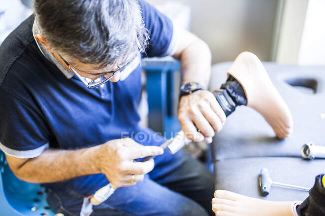 Инженер-протезист рассматривает протез пациента и улучшает материал в его мастерской — стоковое фото