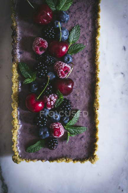 Gustosa torta rettangolare decorata con bacche estive su tavolo bianco — Foto stock