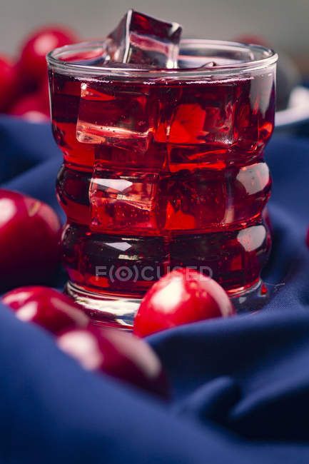 Red beverage near fresh fruits on blue cloth — Stock Photo