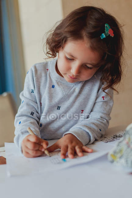 Girl in gray sweater enthusiastically drawing pencil on paper at home — Stock Photo