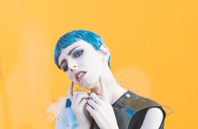 Sensual young woman in trendy futuristic dress on pavement against bright yellow wall — Stock Photo