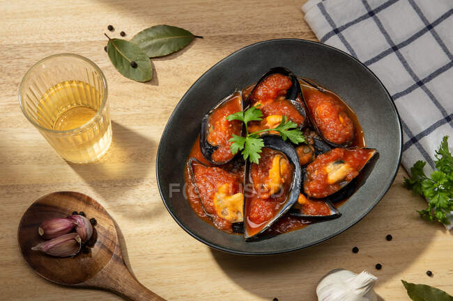 Placa de mejillones de marisco cocidos en salsa de tomate italiano de pie en la mesa de la cocina - foto de stock