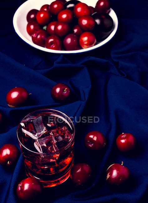Bebida vermelha perto de frutas frescas em pano azul — Fotografia de Stock