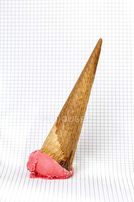 Cono de helado caído sobre papel gráfico - foto de stock