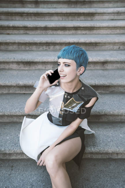 Зверху молода жінка з коротким блакитним волоссям і в модній футуристичній сукні з телефоном на вулицях — стокове фото