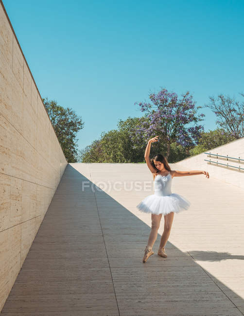 Bailarina realizando com levantar as mãos e esticar as pernas fora em dia ensolarado brilhante — Fotografia de Stock