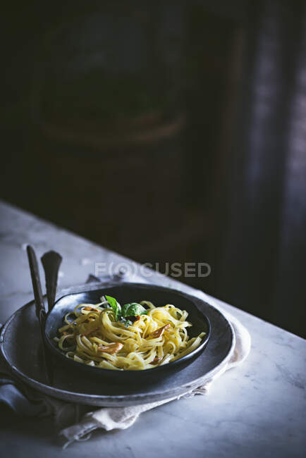 De arriba la pasta apetitosa con hortalizas la albahaca en la escudilla negra a la mesa servida - foto de stock