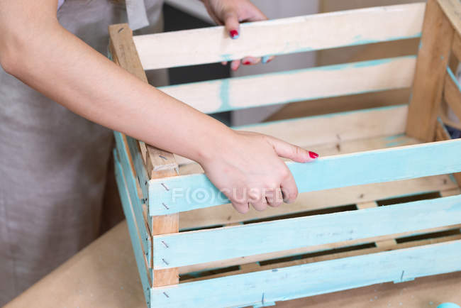 Крупный план женских рук с раскрашенной синей деревянной коробкой — стоковое фото