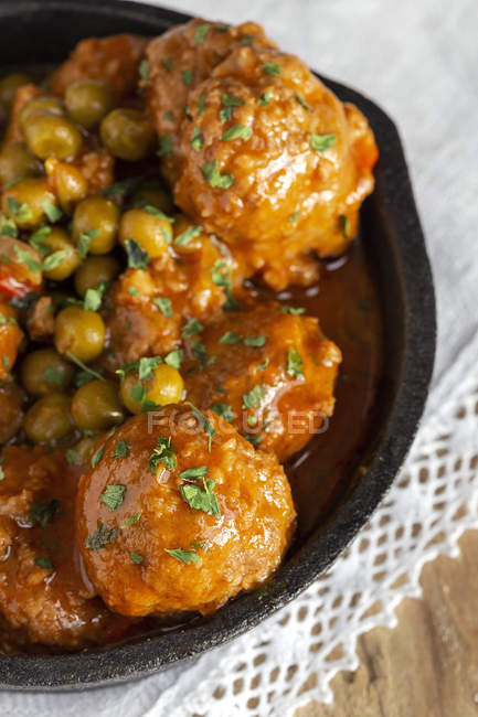 Von oben heiße Pfanne mit gekochten leckeren Fleischbällchen und grünen Erbsen auf weißer Tischdecke — Stockfoto