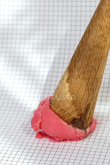 Cono de helado caído sobre papel gráfico - foto de stock