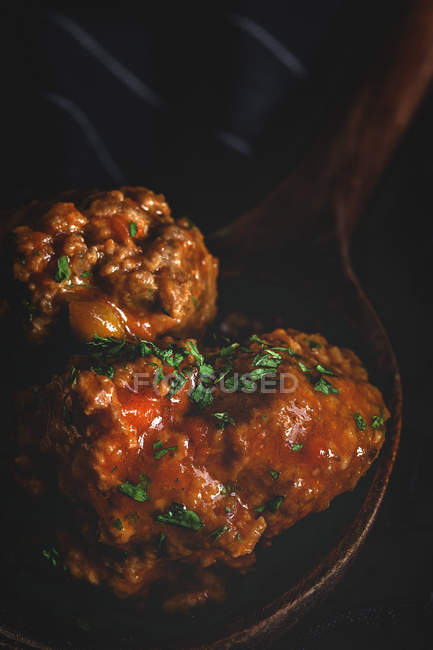 Зверху апетитні м'ясні кульки в коричневому дерев'яному ковші на чорному смугастому рушнику — стокове фото