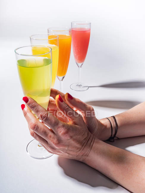 Le mani femminili che tengono il vetro di vetro di succo su sfondo bianco — Foto stock