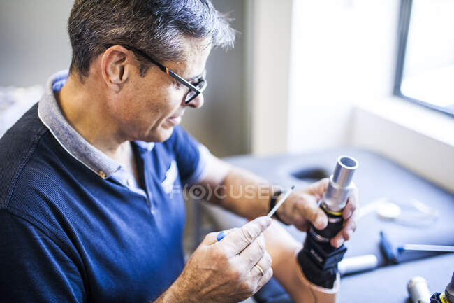 Prothetik-Ingenieur überprüft die Prothese eines Patienten und verbessert das Material in seiner Werkstatt — Stockfoto
