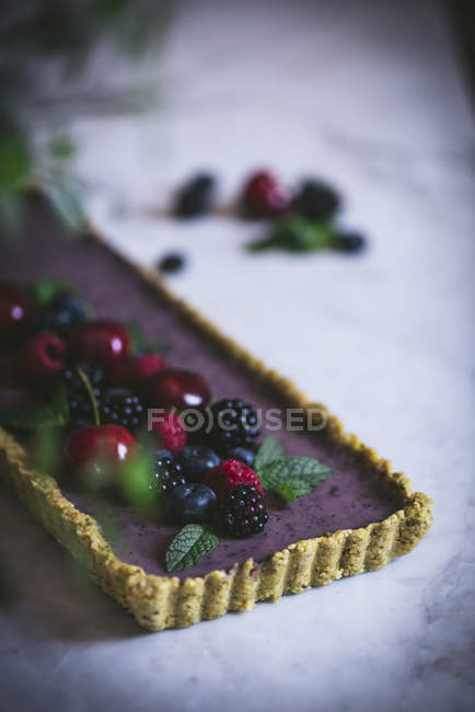 Tasty rectangular cake decorated with summer berries on white table — Stock Photo