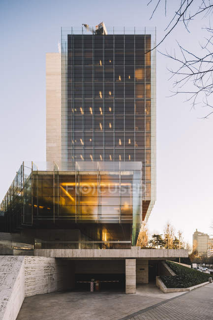 Elegante grattacielo di vetro con parcheggio che riflette il sole nella giornata luminosa in centro — Foto stock