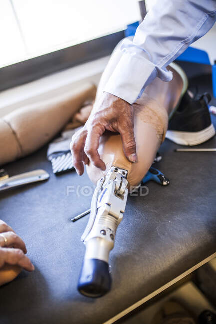 Engenheiro protético irreconhecível revisando a prótese de um paciente e melhorando o material em sua oficina — Fotografia de Stock