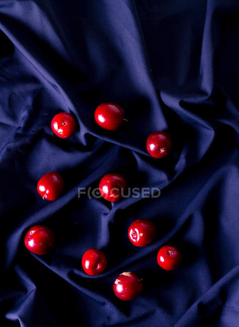 Зверху купа стиглих солодких слив, поміщених на зморшкувату синю тканину — стокове фото