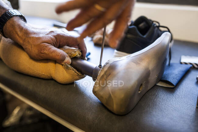 Ingénieur en prothèse méconnaissable examinant la prothèse d'un patient et améliorant le matériel dans son atelier — Photo de stock