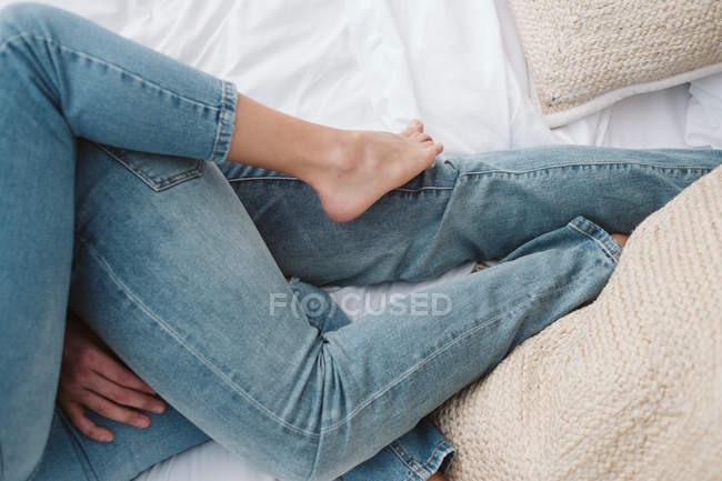 Обрезанный вид на ноги в джинсах романтической пары влюбленной обнимающейся в спальне — стоковое фото