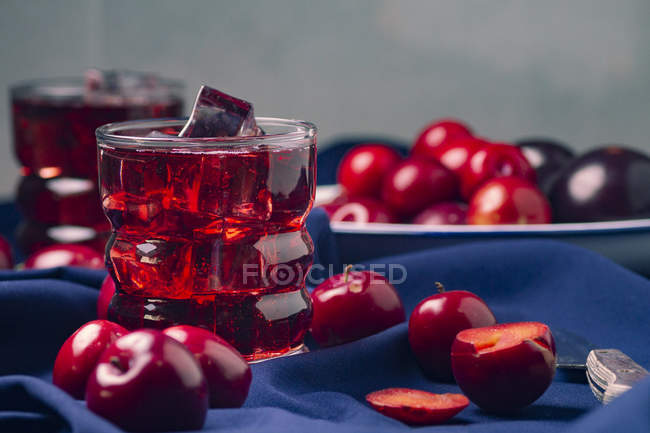 Boisson rouge près des fruits frais sur tissu bleu — Photo de stock