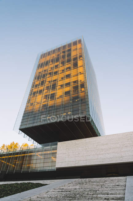 Arranha-céu de vidro elegante refletindo sol em dia brilhante no centro da cidade — Fotografia de Stock