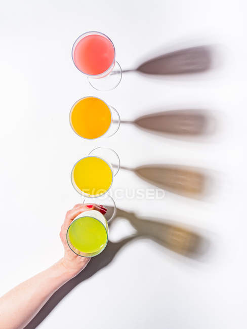 Mão feminina segurando vidro de vidro de suco no fundo branco — Fotografia de Stock