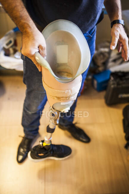 Unerkennbarer Prothetik-Ingenieur begutachtet die Prothese eines Patienten und verbessert das Material in seiner Werkstatt — Stockfoto