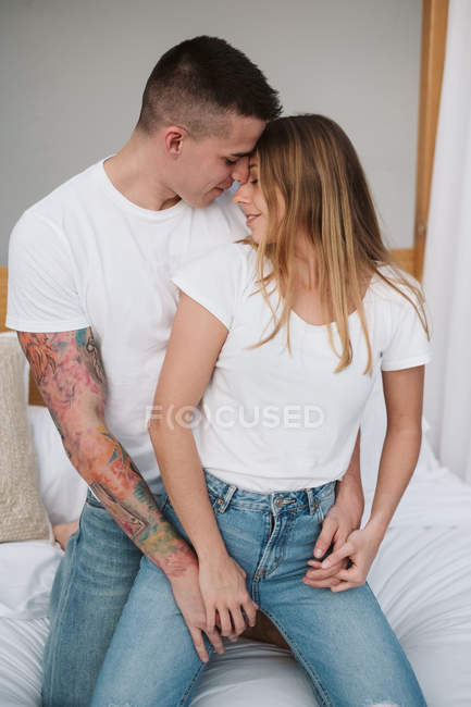 Schöne junge Frau in weißem T-Shirt, Händchen haltend und sich mit Mann im Schlafzimmer anschauend — Stockfoto