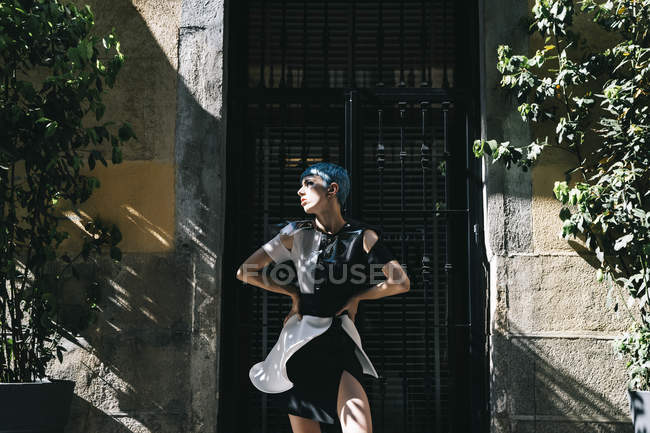 Junge Frau in futuristischem Kleid steht im Sonnenlicht auf der Straße vor altem Gebäude — Stockfoto