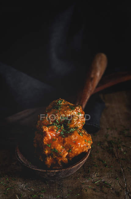 From above appetizing meatballs in brown wooden ladle on black striped towel — Stock Photo