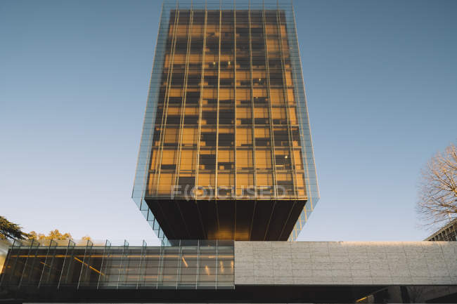 Arranha-céu de vidro elegante refletindo sol em dia brilhante no centro da cidade — Fotografia de Stock