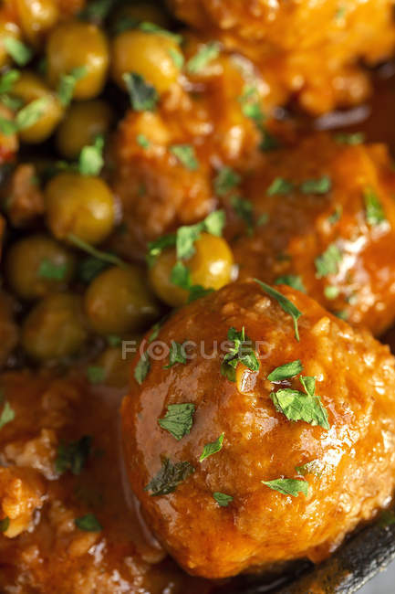 Close up of cooked delicious meatballs and green peas with red sauce — Stock Photo
