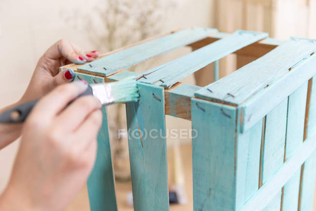 Mãos femininas dor caixa de madeira na cor azul com escova — Fotografia de Stock