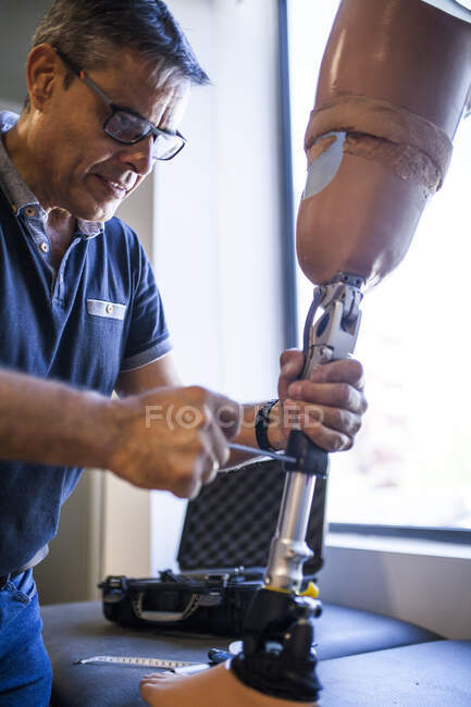 Ingeniero protésico revisando la prótesis de un paciente y mejorando el material en su taller - foto de stock